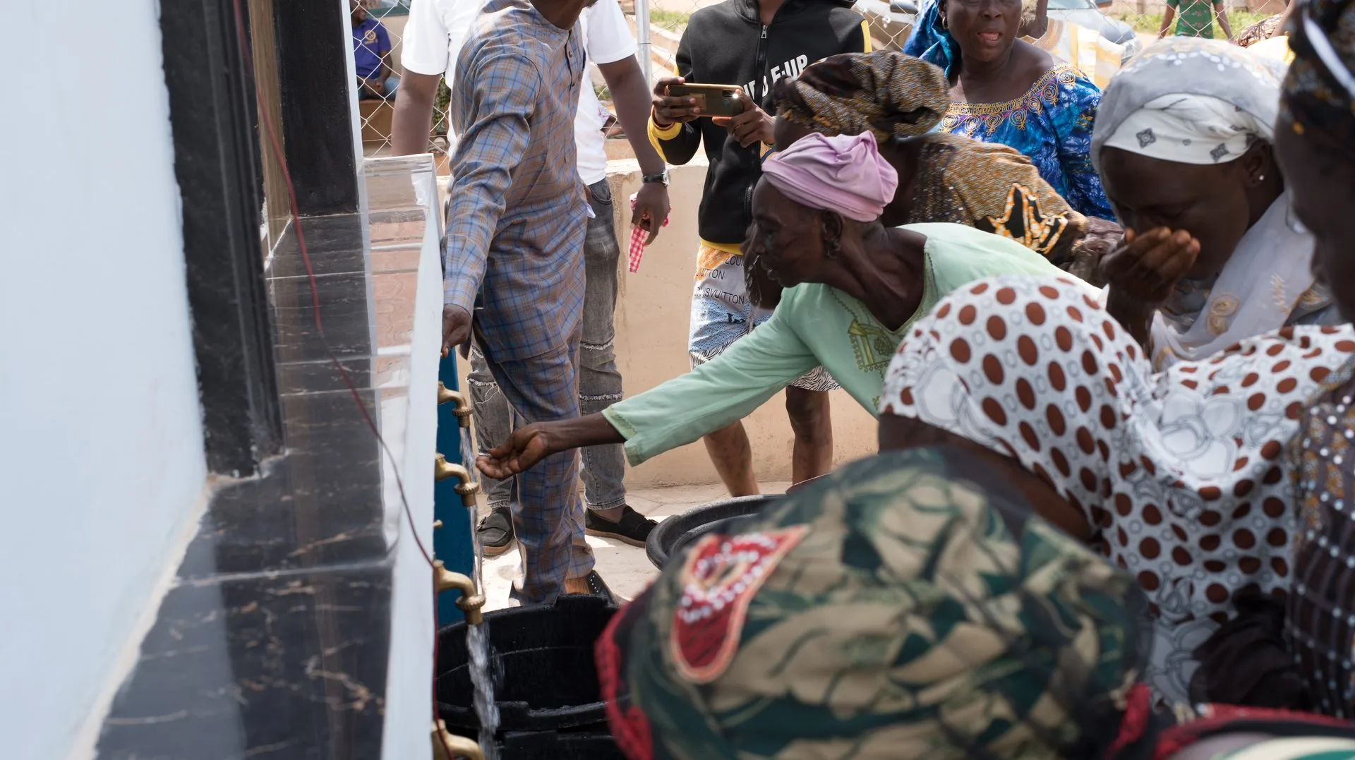 A mother fetches clean water from a Fairaction Smart Water Kiosk in Abeku, Nigeria.