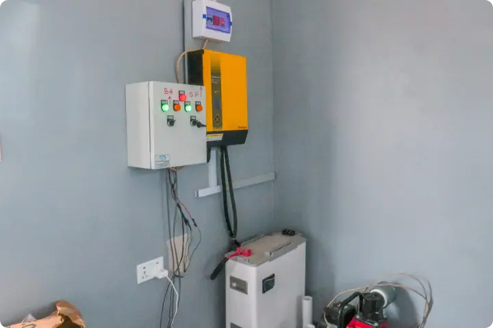 A wall-mounted electrical setup with control panels and wiring, featuring a yellow box, switches, and a power outlet in a gray room.